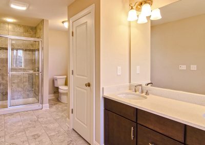 double vanity with large mirror and tiled shower with bench