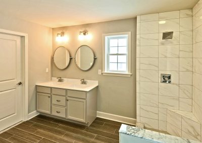 white double vanity with oval mirrors and shower