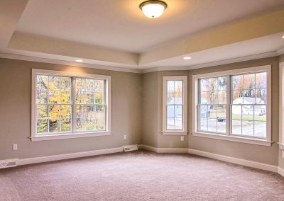 carpeted bedroom with tray ceiling and bay window