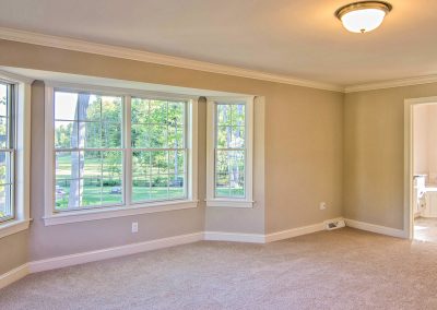 carpeted bedroom with crown molding and bay window