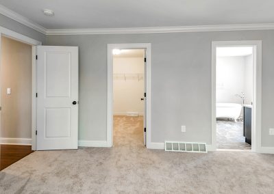 carpeted bedroom with doors to closet and bathroom