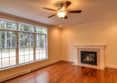 family room with hardwood fireplace and ceiling fan