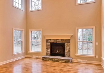 two story room with hardwood floor and raised stone hearth