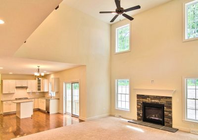 two story family room with ceiling fan and fireplace