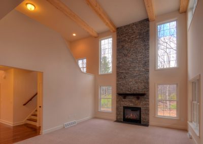 two story family room with ceiling beams and stone fireplace
