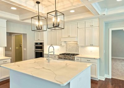 white kitchen with marble counters and coffered ceiling