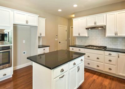 white kitchen dark counters with wall oven