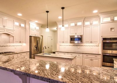white custom kitchen with prep sink and wall ovens