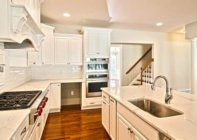 white kitchen with marble counters and gas range