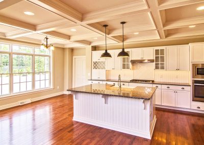 white kitchen with large windows and coffered ceiling