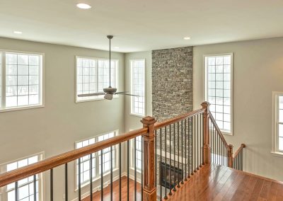 upper landing overlooking family room with iron spindles and wood railings